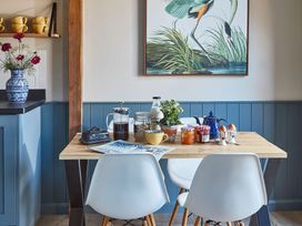 A dining table with breakfast items and two white chairs at The Stables in Galteemore Farm in Avebury near Marlborough