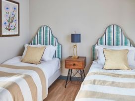 A bedroom with two single beds with patterned headboards and striped blankets at The Stables in Galteemore Farm in Avebury near Marlborough