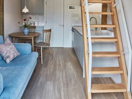 A small kitchen and dining area with wooden stairs and a blue sofa at The Stables in Galteemore Farm in Avebury near Marlborough