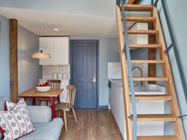 A kitchen and dining area with wooden table red legs wooden chairs blue door and wooden staircase at The Stables Galteemore Farm in Avebury near Marlborough