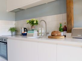 A kitchen countertop with a sink a loaf of bread bottles a kettle plants books and a toaster at The Stables Galteemore Farm in Avebury near Marlborough
