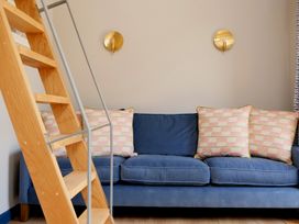 A blue sofa with patterned cushions and a wooden ladder in front at The Stables in Galteemore Farm in Avebury near Marlborough