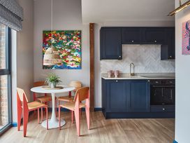 A kitchen and dining area with navy cabinets wooden chairs and a round white table at The Stables Galteemore Farm in Avebury near Marlborough
