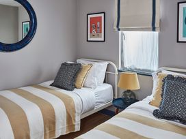 A bedroom with two single beds striped blankets pillows a window a lamp and a circular mirror at The Stables in Galteemore Farm in Avebury near Marlborough