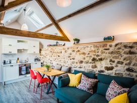 An open kitchen and living area with wood beams stone wall and red chairs at The Stables Galteemore Farm in Avebury near Marlborough