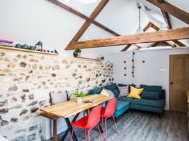 A living area with a wooden dining table red chairs a blue sofa with cushions and exposed wooden beams at The Stables Galteemore Farm in Avebury near Marlborough