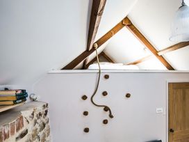 A bedroom loft with a climbing wall and rope ladder next to a wooden door at The Stables in Galteemore Farm in Avebury near Marlborough
