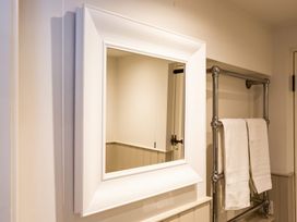 A square wall mirror with a white frame and a metal towel rack with two white towels at The Stables in Galteemore Farm in Avebury near Marlborough