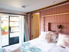 A bedroom with a bed two pillows a folded towel curtain and a door at The Stables in Galteemore Farm in Avebury near Marlborough
