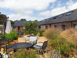 An outdoor patio with metal tables and chairs surrounded by plants and flowers at The Stables Galteemore Farm in Avebury near Marlborough