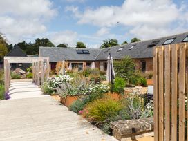 A garden with flowers seating areas and umbrellas outside a building with skylights at The Stables in Galteemore Farm in Avebury near Marlborough