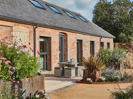 An outdoor area with a brick building having multiple doors and skylights and various plants at The Stables in Galteemore Farm in Avebury near Marlborough