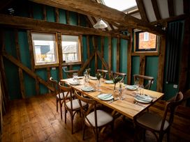 A dining room with a wooden table set for six and wooden chairs at The Stables in Galteemore Farm in Avebury near Marlborough