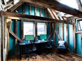 An office room with two computer desks and chairs and a single armchair with cushions at The Stables in Galteemore Farm in Avebury near Marlborough