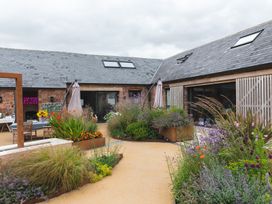 An outdoor courtyard with plants and flowers in raised beds and patio furniture at The Stables in Galteemore Farm in Avebury near Marlborough