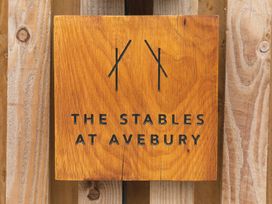 A wooden sign with The Stables at Avebury engraved on it mounted on a wooden wall at The Stables at Avebury near Marlborough