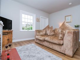 A living room with a brown sofa a television on wooden cabinet and two glasses of wine on the floor at Fern Cottage in North Dalton near Great Driffield