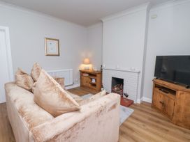 A living room with a beige sofa a white brick fireplace a wooden TV stand and a wooden side table at Fern Cottage in North Dalton near Great Driffield