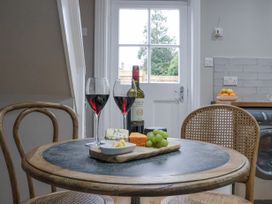 A round table with two glasses of red wine a bottle of wine cheese grapes and two chairs in a kitchen at Fern Cottage in North Dalton near Great Driffield