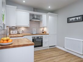 A kitchen with white cabinets wooden countertops a bowl of fruit a stainless steel oven and hood at Fern Cottage in North Dalton near Great Driffield