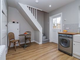 A kitchen with a washing machine wooden floor under stairs with table and two chairs at Fern Cottage in North Dalton near Great Driffield