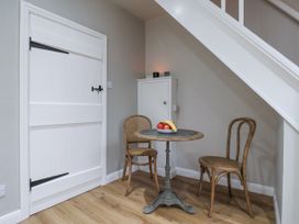 A small dining area with a round table and two wooden chairs under a staircase at Fern Cottage in North Dalton near Great Driffield