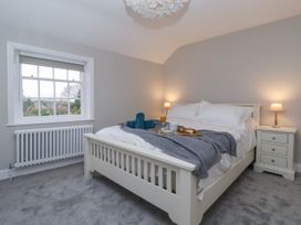 A bedroom with a white bed frame gray blanket and bedside tables with lamps at Fern Cottage in North Dalton near Great Driffield