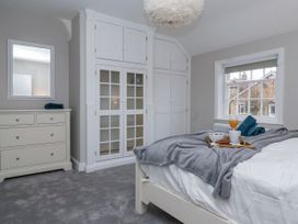 A bedroom with a bed, built-in wardrobes, chest of drawers, and a window at Fern Cottage in North Dalton near Great Driffield