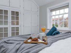 A bedroom with a breakfast tray on a grey blanket and white cabinets at Fern Cottage in North Dalton near Great Driffield
