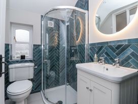 A bathroom with a shower enclosure toilet and sink with a round lit mirror at Fern Cottage in North Dalton near Great Driffield