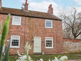 A brick house with a pale green door and white framed windows with flowers in front at Fern Cottage in North Dalton near Great Driffield