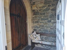 An entrance with a wooden door and stone wall at Ashleigh House 
