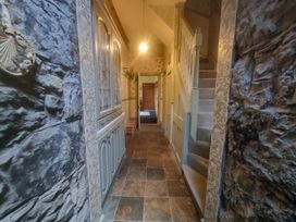 A hallway with a staircase and shelves at Ashleigh House