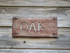 A wooden sign with the word OAK carved on a wooden wall at Oak Lodge in Rosliston