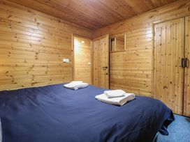 A bedroom with wood panel walls ceiling double bed with towels and a wooden wardrobe at Oak Lodge in Rosliston
