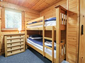 A bedroom with a wooden bunk bed a chest of drawers and a window with blinds at Oak Lodge in Rosliston