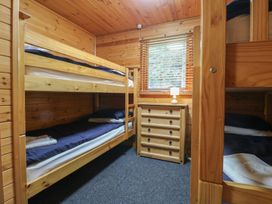 A bedroom with bunk beds a chest of drawers and a window with blinds at Oak Lodge in Rosliston