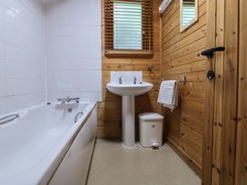 A bathroom with a bathtub sink towel rail and wooden walls at Oak Lodge in Rosliston