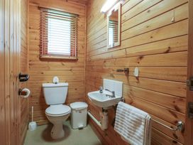 A small bathroom with a toilet sink trash bin and towel rack with wooden panel walls at Oak Lodge in Rosliston