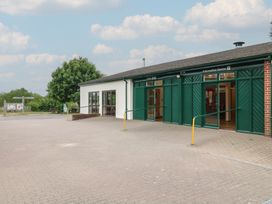 An information centre building with green doors and windows and a paved area outside at Oak Lodge in Rosliston