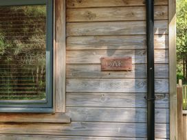 A wooden cabin wall with a window and a sign that says oak at Oak Lodge Rosliston