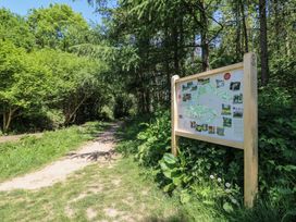 A dirt path through a forested area with a wooden information board on the right Oak Lodge Rosliston