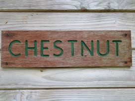 A wooden sign with the word chestnut mounted on a wooden wall at Chestnut Lodge in Rosliston