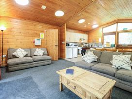A living area with two sofas a wooden coffee table and a kitchen with cabinets and appliances at Chestnut Lodge in Rosliston