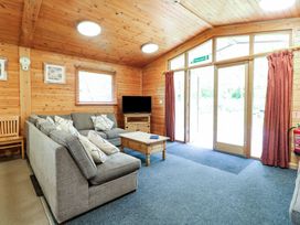 A sitting area with gray sofas a wooden coffee table and a television in a wooden room at Chestnut Lodge in Rosliston