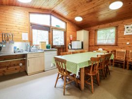 A kitchen dining area with a table covered by a green polka dot tablecloth and wooden chairs at Chestnut Lodge in Rosliston