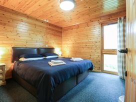 A bedroom with a double bed towels on bed wooden walls window with curtains at Chestnut Lodge in Rosliston