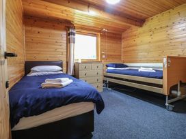 A bedroom with two single beds a chest of drawers and a window at Chestnut Lodge in Rosliston