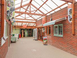 An indoor walkway with brick walls wooden beams a display stand windows and shop signage at Rosliston Forestry Centre
