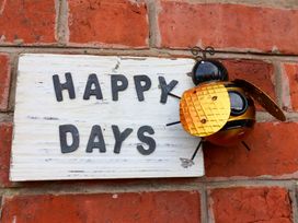 A sign with the words Happy Days and a decorative bee attached to a brick wall at Happy Days in Scarborough